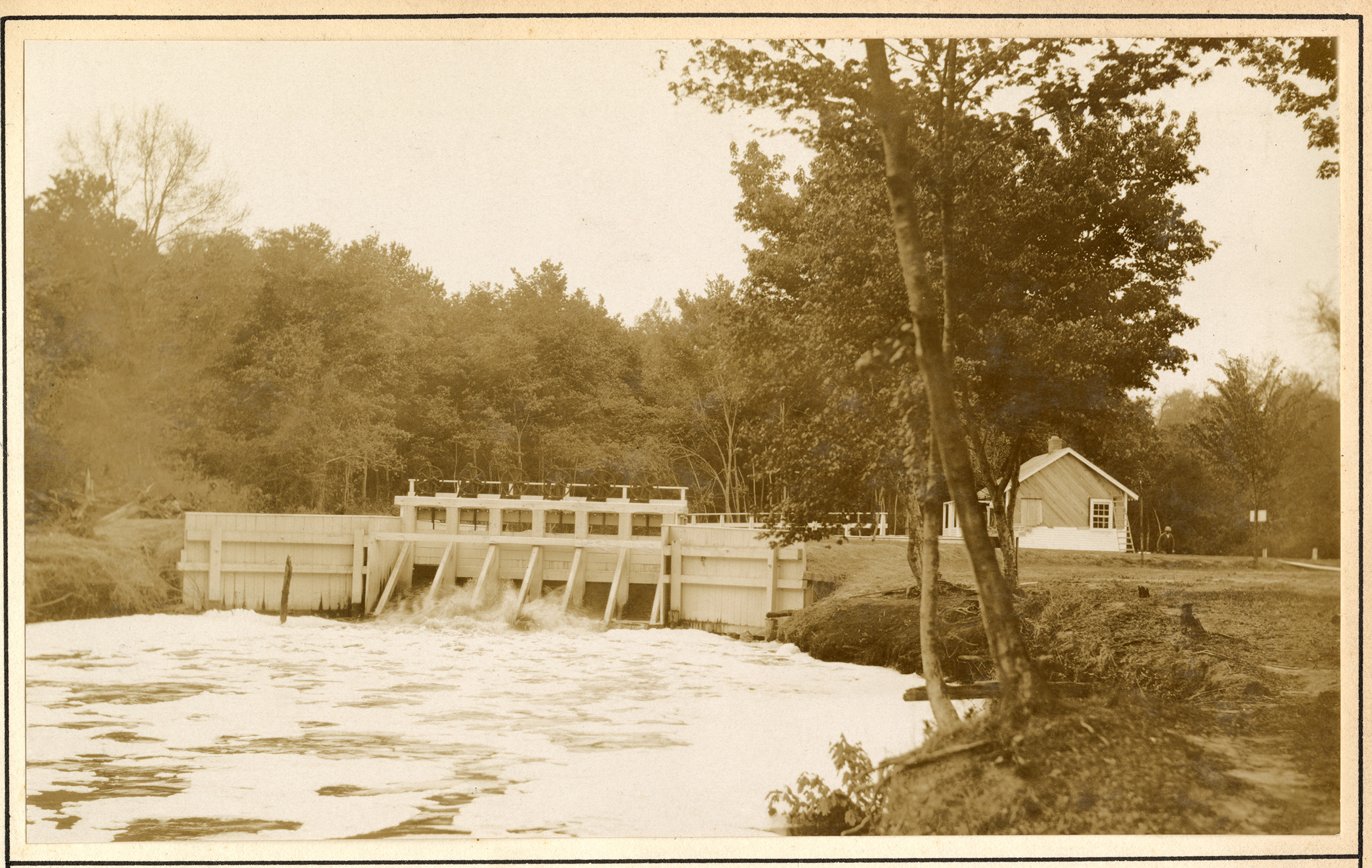 Small spillway releasing water with house in background